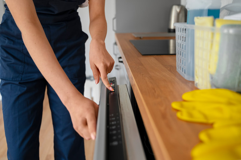 Close-up of a gloved hand pressing the control panel of a built-in dishwasher in a kitchen. Close-up of a gloved hand pressing the control panel of a built-in dishwasher in a kitchen.