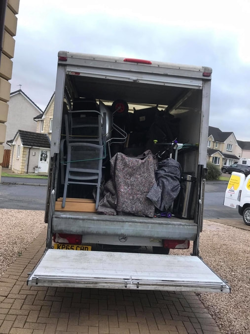 The open back of a man-with-a-van removal vehicle loaded with a chair, bags and furniture ready for transport in Nottingham.